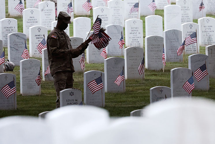 Photo of soldier placing flags at Arlington National Cemetary