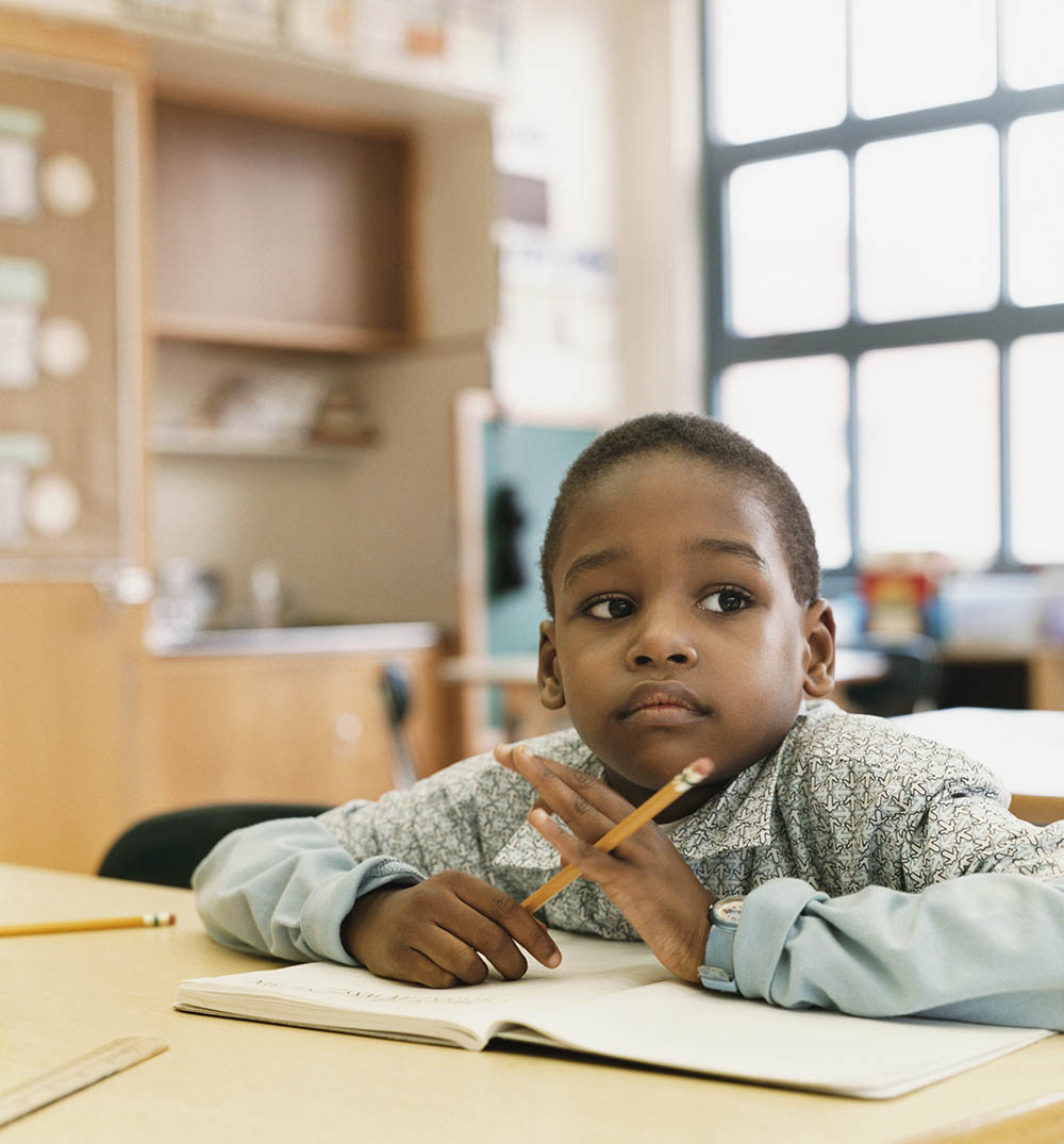 Schoolboy Sits at a Table Daydreaming