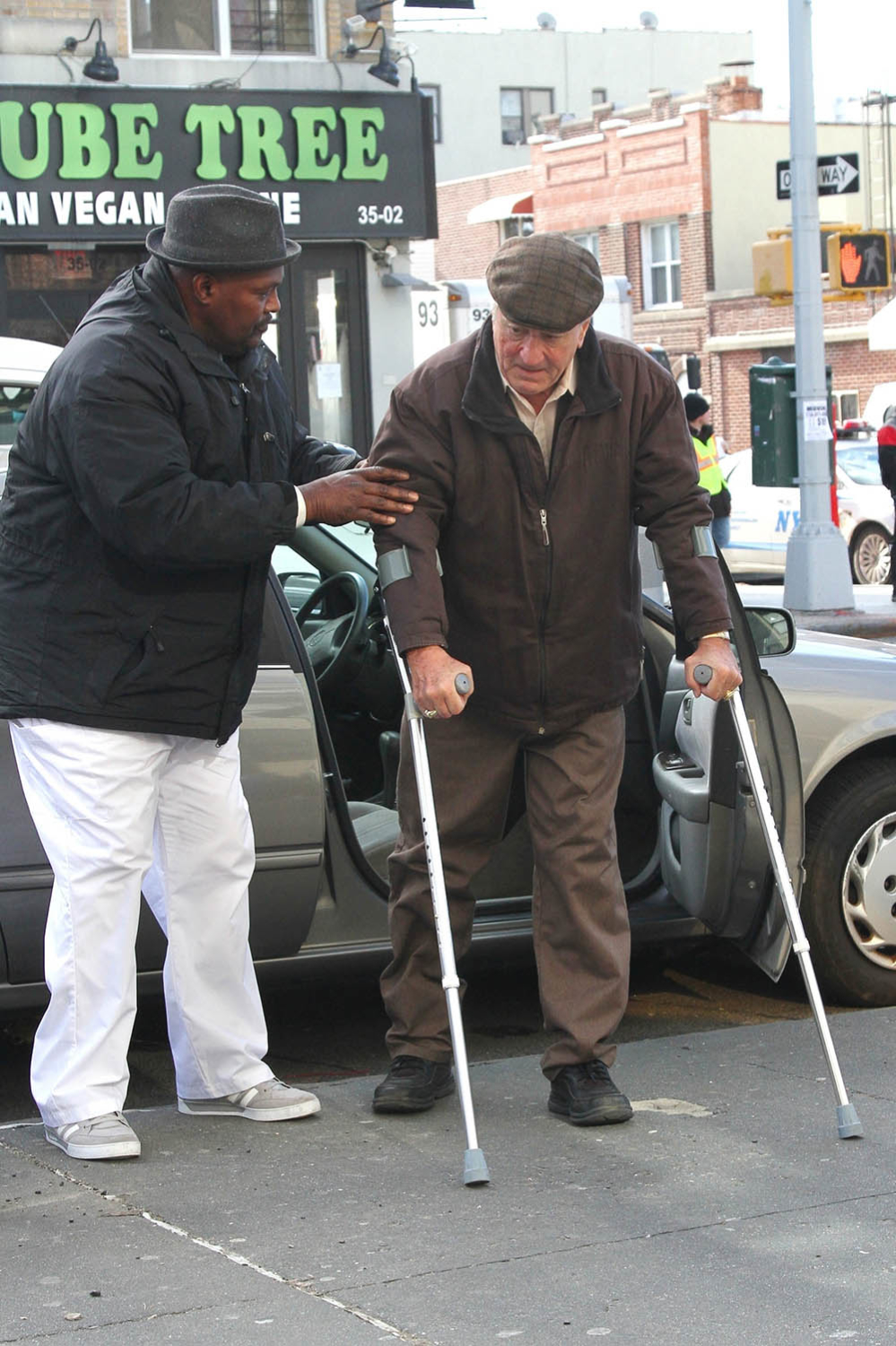 An older looking Robert De Niro is assisted out of his car while filming The Irishman