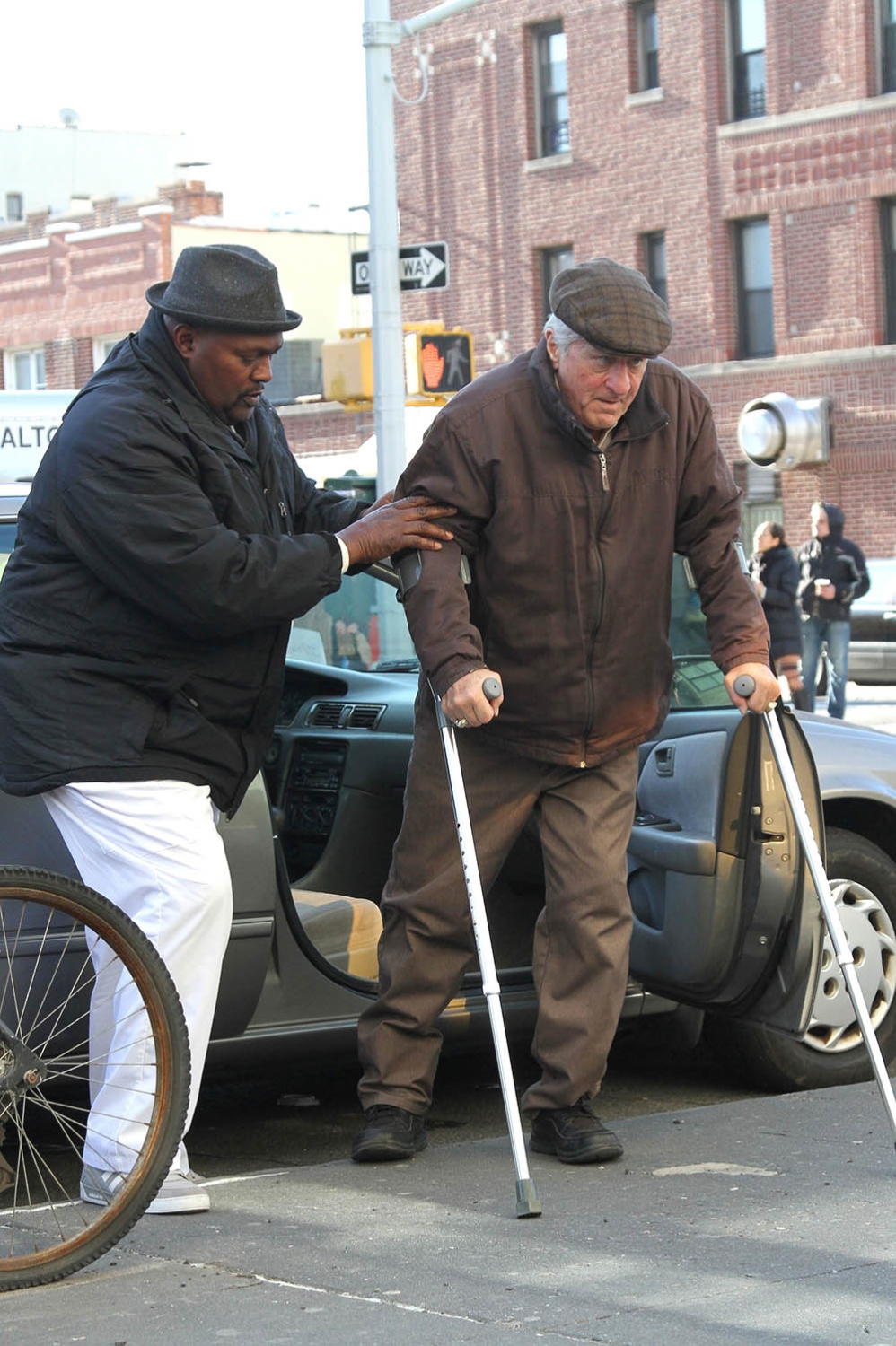 An older looking Robert De Niro is assisted out of his car while filming The Irishman