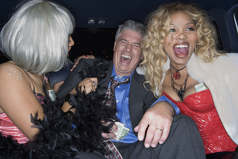 Stock photo - Middle-aged man laughing in limousine with prostitutes