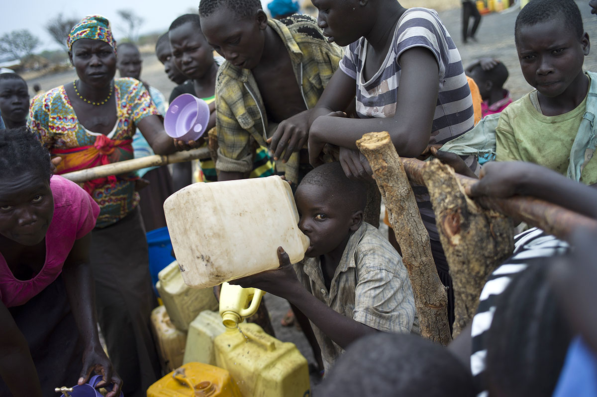 South Sudanese Refugees collect and drink water at a well