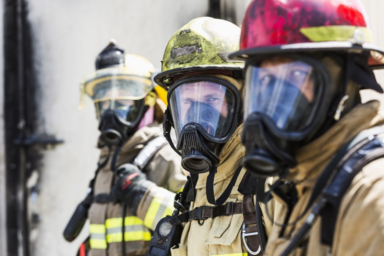 A group of three multiracial firefighters wearing protective gear