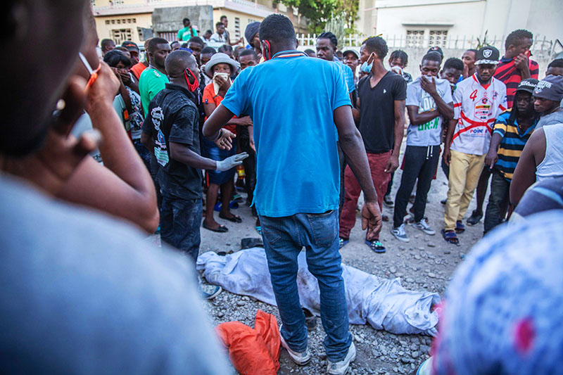 LES CAYES, HAITI – AUGUST 15: Haitians look over a casualty in the 7.2 ...