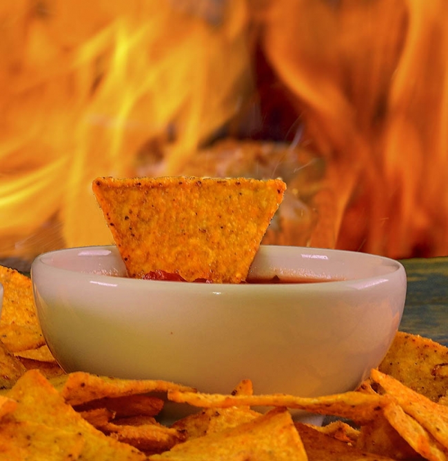 Stock photo – Hot Nacho tortilla chips with salsa dip on flaming
